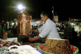 Image du Maroc Professionnelle de  Vendeur de Khoudenjale, une infusion tonifiante constituée de plusieurs herbes aromatiques : elle réchauffe et ouvre l’appétit, aphrodisiaque se prend avant ou après repas. sur la place Jamaa El Fana plusieurs vendeurs de cette tisane sont installés sur la place, ils la proposent avec une sorte de farine cuite mélangées aux amandes, graines de sésames, cacao… Une atmosphère un peu magique dans ces lieus au centre de Marrakech, le 1er Mars 2004. (Photo / Abdeljalil Bounhar)

 